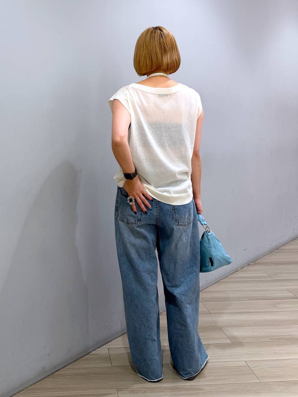 ブルー系のデニムパンツ、ホワイト系のTシャツ/カットソー、ブルー系のハンドバッグを着用したレディースの夏コーディネートの3枚目の写真