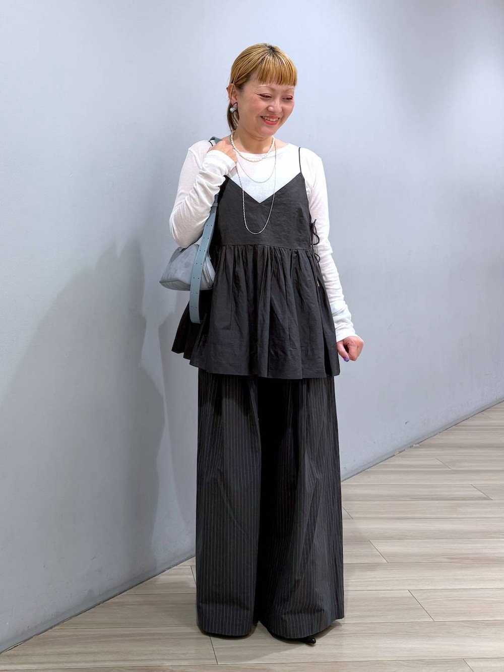 ブルー系のハンドバッグ、ホワイト系のTシャツ/カットソー、グレー系のキャミソールを着用したレディースの冬コーディネートの5枚目の写真