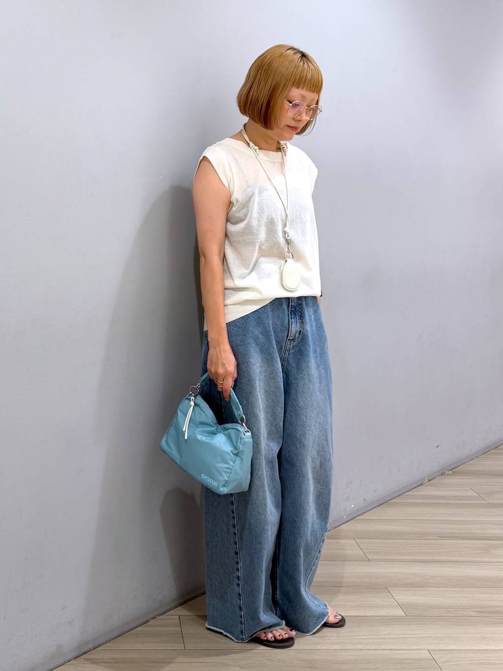 ブルー系のデニムパンツ、ホワイト系のTシャツ/カットソー、ブルー系のハンドバッグを着用したレディースの夏コーディネートの2枚目の写真