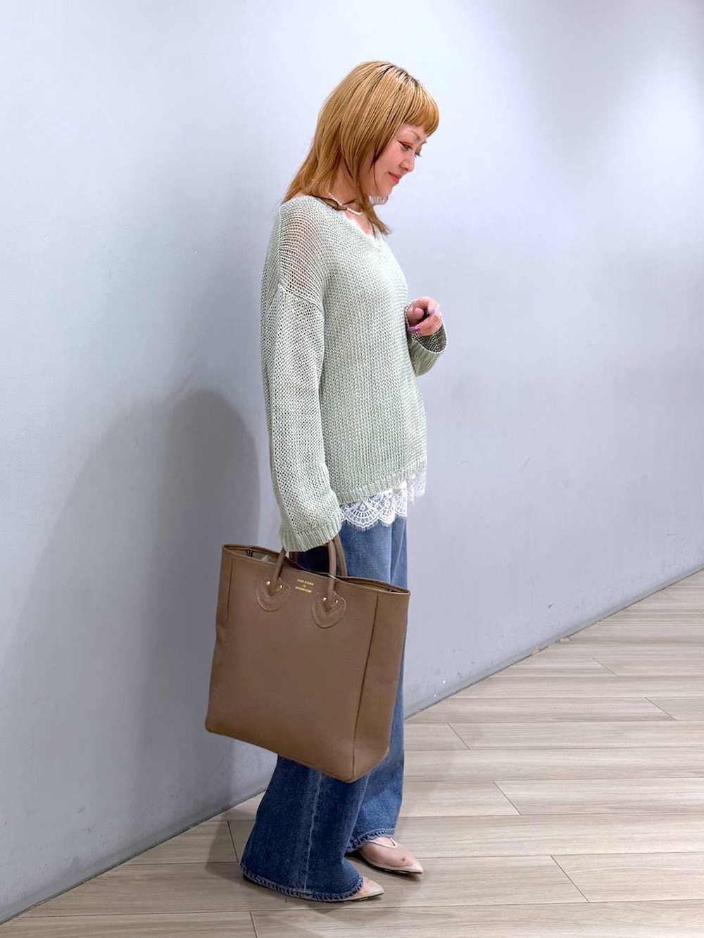 ベージュ系のパンプス、ブルー系のデニムパンツ、ホワイト系のキャミソールを着用したレディースの春コーディネートの3枚目の写真