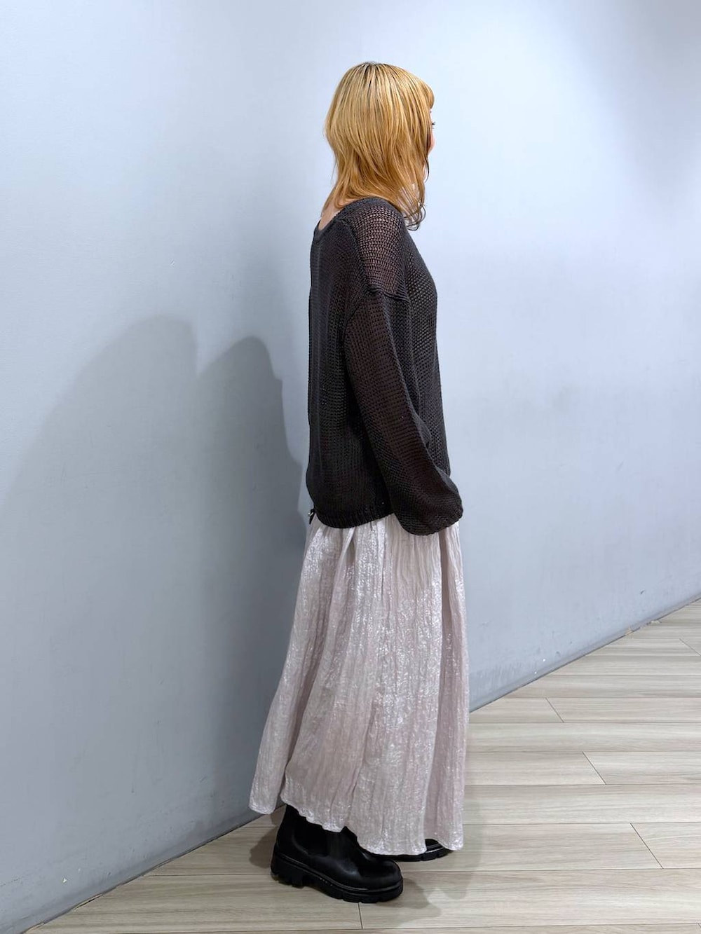 ブラック系のブーツ、ブラック系のボストンバッグ、シルバー系のスカートを着用したレディースの春コーディネートの2枚目の写真