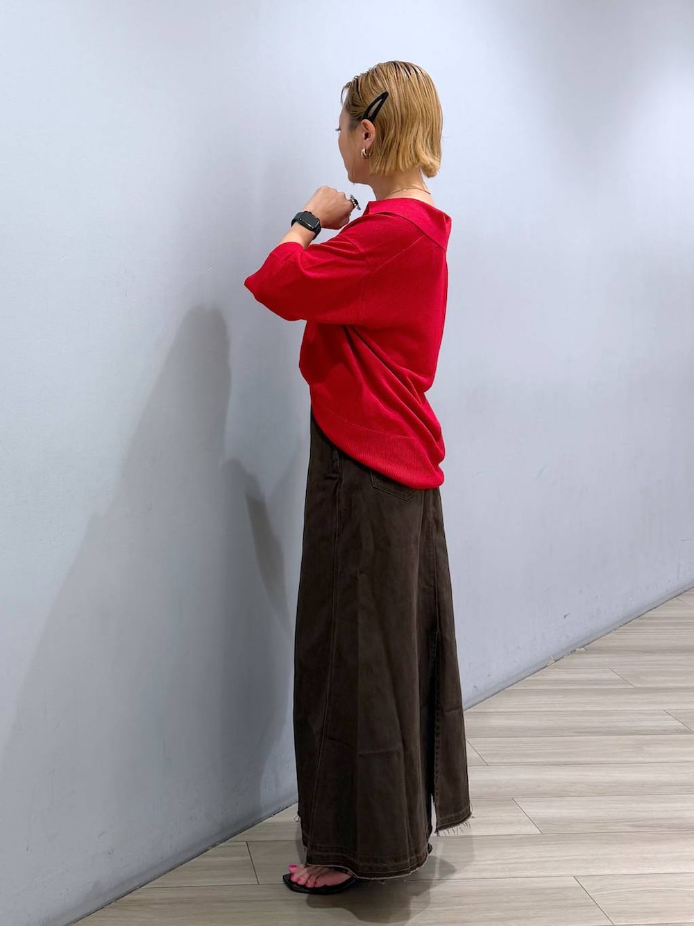 レッド系のニット/セーター、ブラウン系のスカート、ブラウン系のサンダルを着用したレディースの夏コーディネートの2枚目の写真