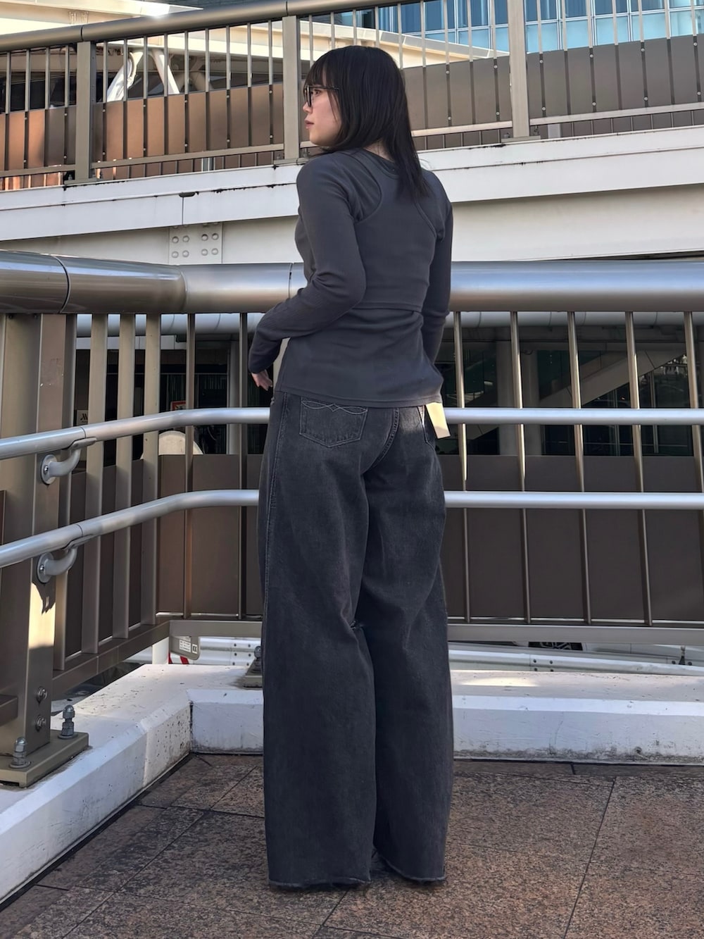 ブラック系のデニムパンツ、グレー系のTシャツ/カットソー、ブラック系のブーツを着用したレディースの春コーディネートの3枚目の写真