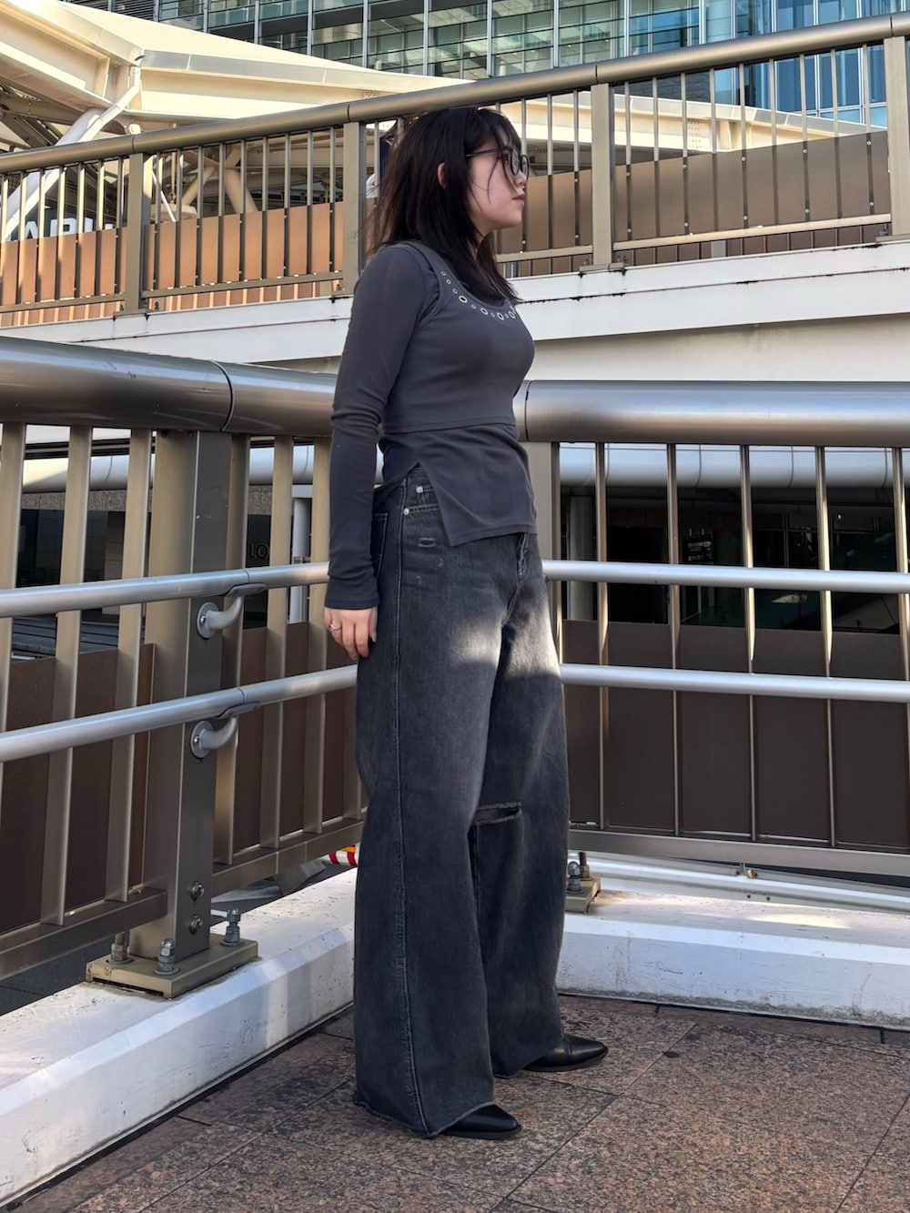 ブラック系のデニムパンツ、グレー系のTシャツ/カットソー、ブラック系のブーツを着用したレディースの春コーディネートの2枚目の写真