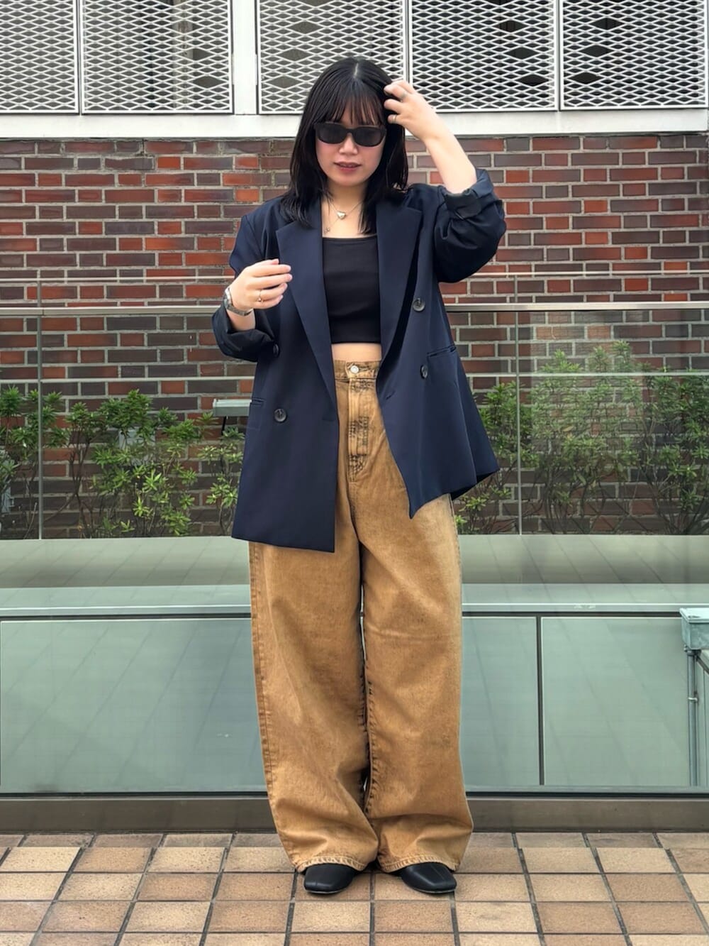 ブラウン系のデニムパンツ、ブルー系のテーラードジャケット、ブラック系のキャミソールを着用したレディースの春コーディネートの2枚目の写真