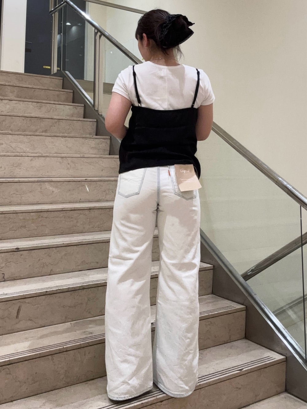 ホワイト系のデニムパンツ、ブラック系のブーツ、ブラック系のキャミソールを着用したレディースの春コーディネートの3枚目の写真