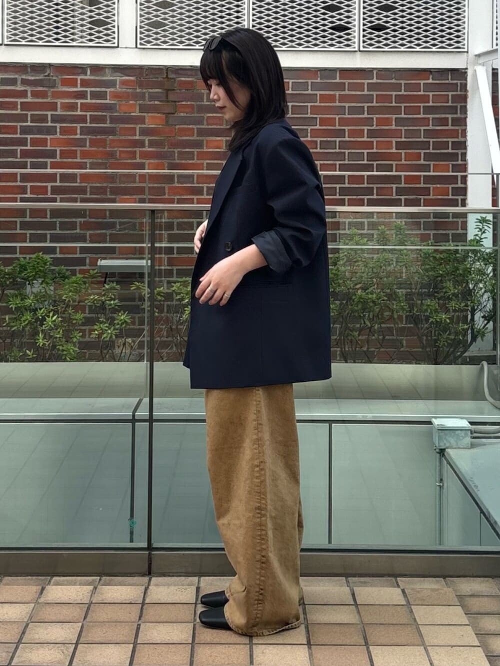 ブラウン系のデニムパンツ、ブルー系のテーラードジャケット、ブラック系のキャミソールを着用したレディースの春コーディネートの3枚目の写真