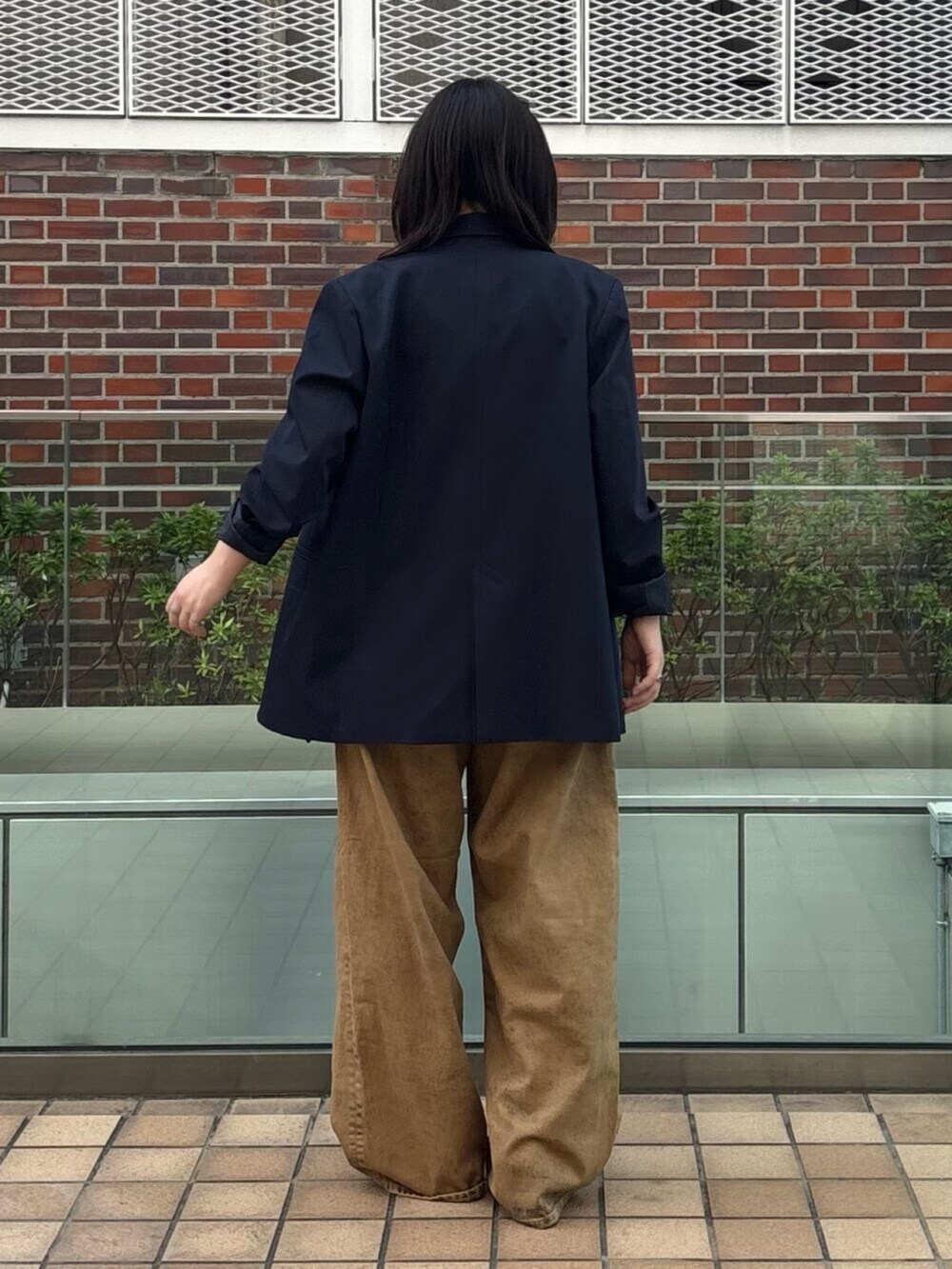 ブラウン系のデニムパンツ、ブルー系のテーラードジャケット、ブラック系のキャミソールを着用したレディースの春コーディネートの4枚目の写真