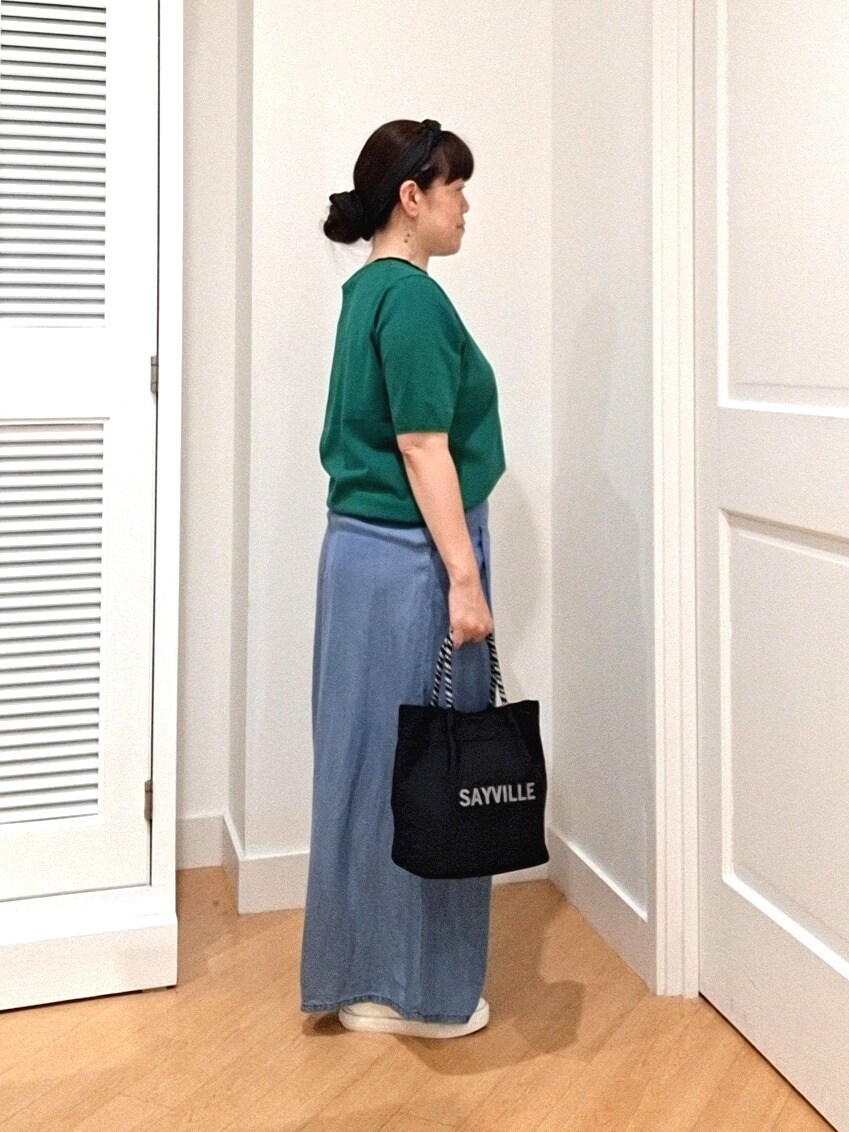 グリーン系のニット/セーター、ブルー系のデニムパンツ、ホワイト系のスニーカーを着用したレディースの夏コーディネートの2枚目の写真