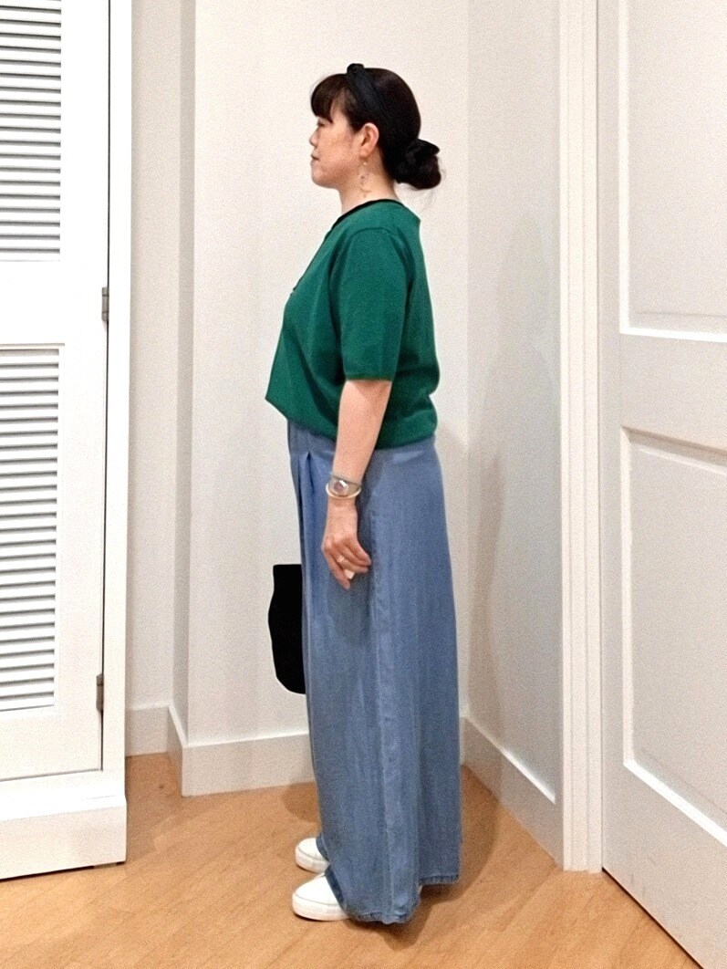 グリーン系のニット/セーター、ブルー系のデニムパンツ、ホワイト系のスニーカーを着用したレディースの夏コーディネートの4枚目の写真