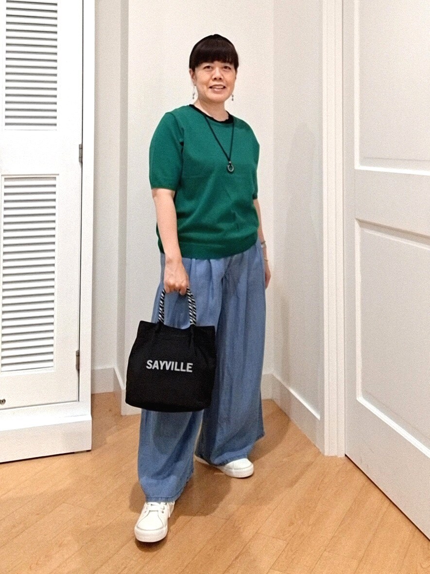 グリーン系のニット/セーター、ブルー系のデニムパンツ、ホワイト系のスニーカーを着用したレディースの夏コーディネートの5枚目の写真