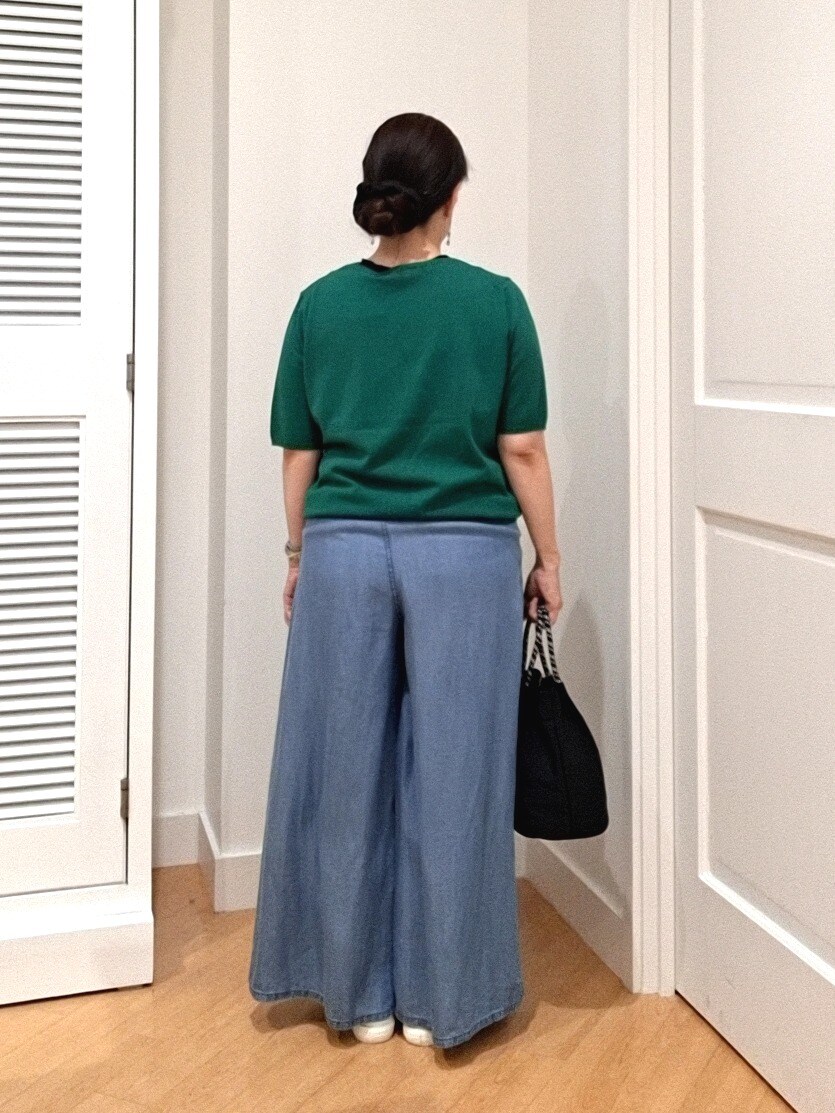 グリーン系のニット/セーター、ブルー系のデニムパンツ、ホワイト系のスニーカーを着用したレディースの夏コーディネートの3枚目の写真