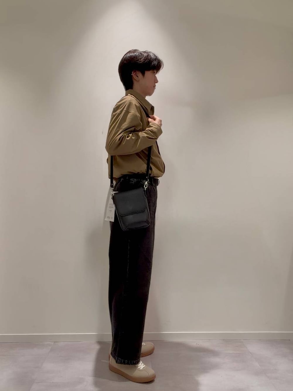 ベージュ系のスニーカー、ベージュ系のミリタリージャケット、ブラック系のデニムパンツを着用したメンズの秋コーディネートの3枚目の写真