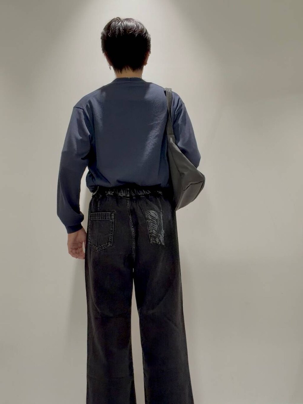 ブラック系のデニムパンツ、グレー系のその他シューズ、ホワイト系のTシャツ/カットソーを着用したメンズの秋コーディネートの3枚目の写真