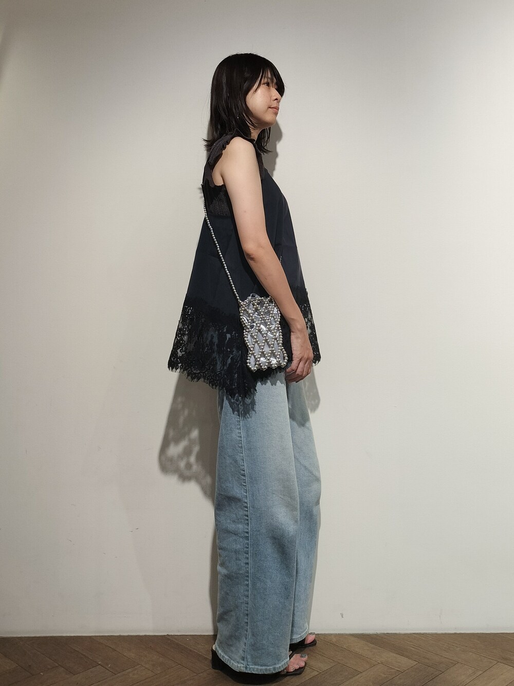 グレー系のニット/セーター、ブルー系のシャツ/ブラウス、ブルー系のデニムパンツを着用したレディースの夏コーディネートの4枚目の写真