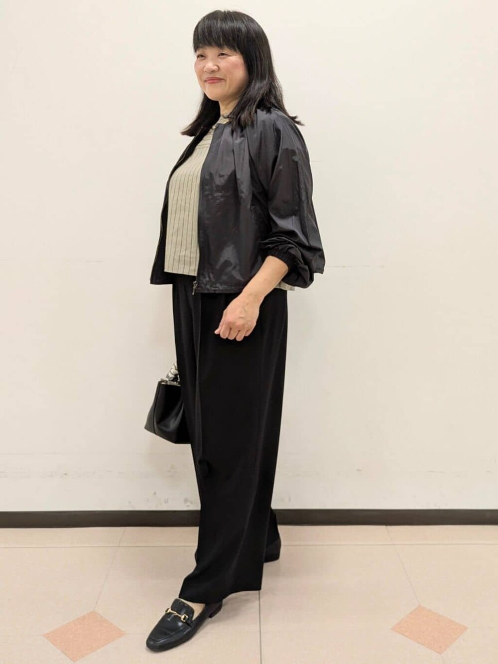 ベージュ系のシャツ/ブラウス、ブラック系のブルゾン、ブラック系のトートバッグを着用したレディースの春コーディネートの5枚目の写真