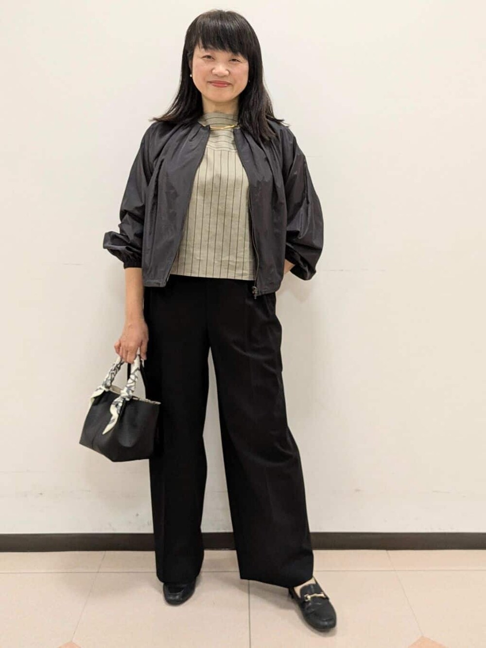 ベージュ系のシャツ/ブラウス、ブラック系のブルゾン、ブラック系のトートバッグを着用したレディースの春コーディネートの3枚目の写真