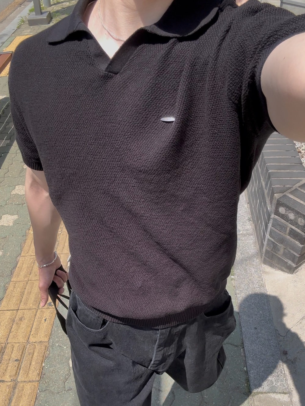 ブラック系のポロシャツ、ブラック系のデニムパンツ、ブラック系のスニーカーを着用したメンズの夏コーディネートの2枚目の写真