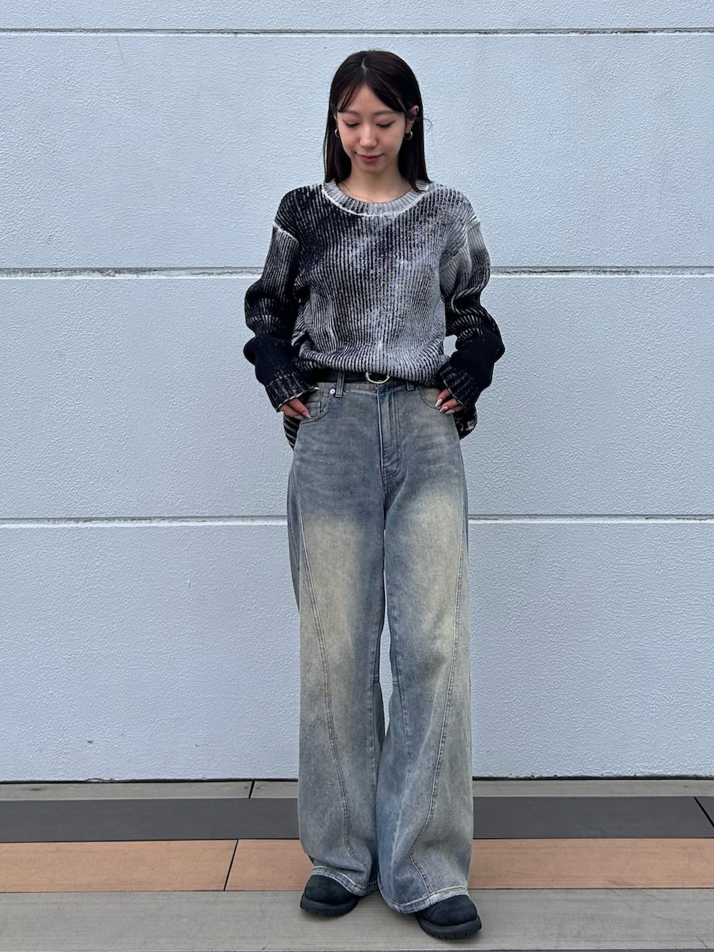 ブルー系のデニムパンツ、ホワイト系のニット/セーター、ブラック系のベルトを着用したレディースの秋コーディネートの2枚目の写真