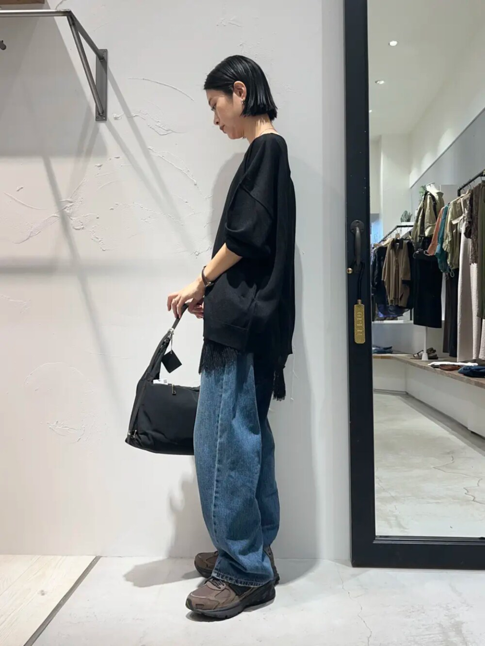 ブルー系のデニムパンツ、ブラック系のキャミソール、ブラック系のニット/セーターを着用したレディースの秋コーディネートの2枚目の写真