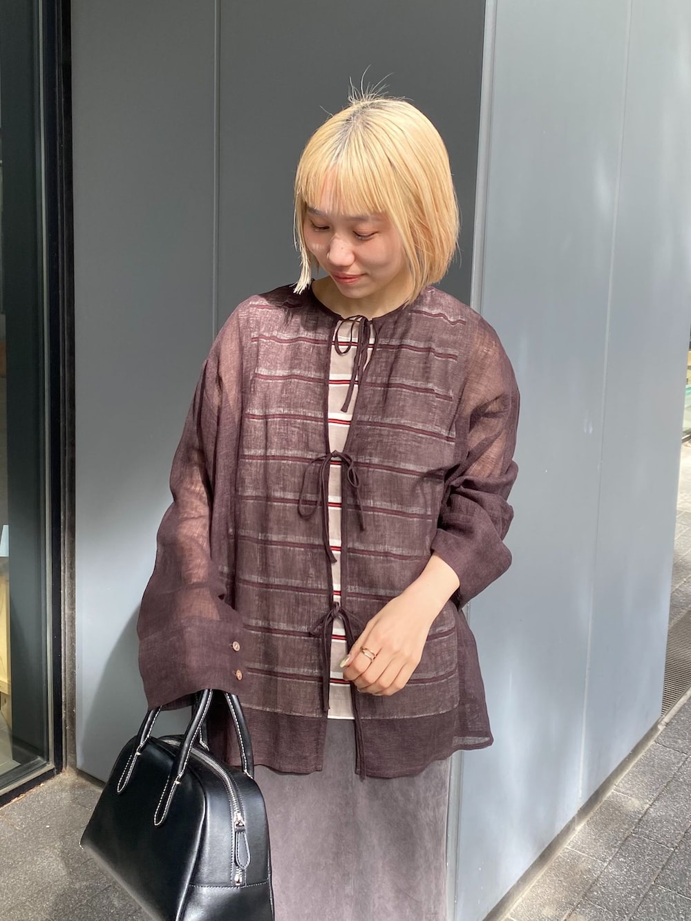 ブラウン系のシャツ/ブラウス、ブラウン系のスカート、ベージュ系のTシャツ/カットソーを着用したレディースの春コーディネートの3枚目の写真