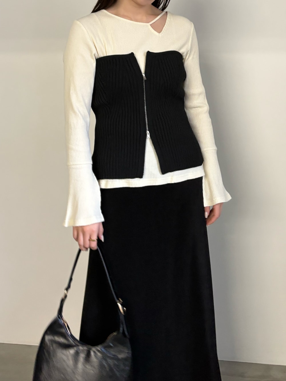 ブラック系のベスト、ブラック系のスカート、ブラック系のハンドバッグを着用したレディースの冬コーディネートの4枚目の写真