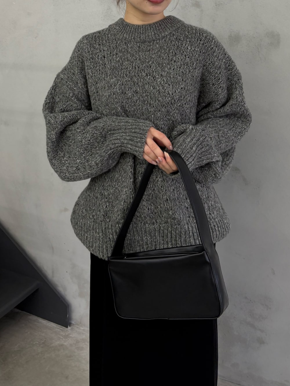 グレー系のニット/セーター、ブラック系のスカート、ブラック系のショルダーバッグを着用したレディースの冬コーディネートの4枚目の写真