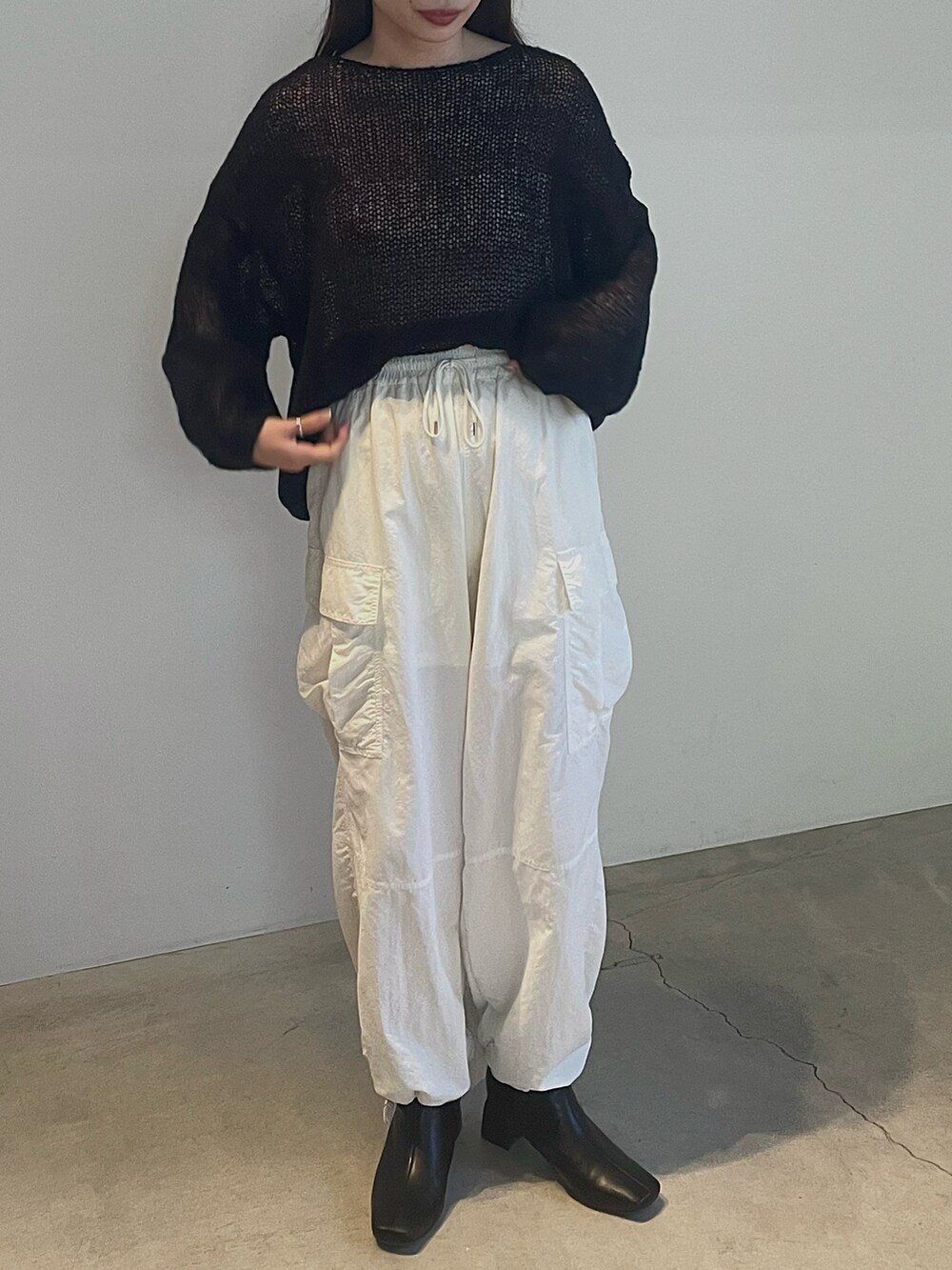 ブラック系のニット/セーター、ホワイト系のカーゴパンツを着用したレディースの夏コーディネートの2枚目の写真