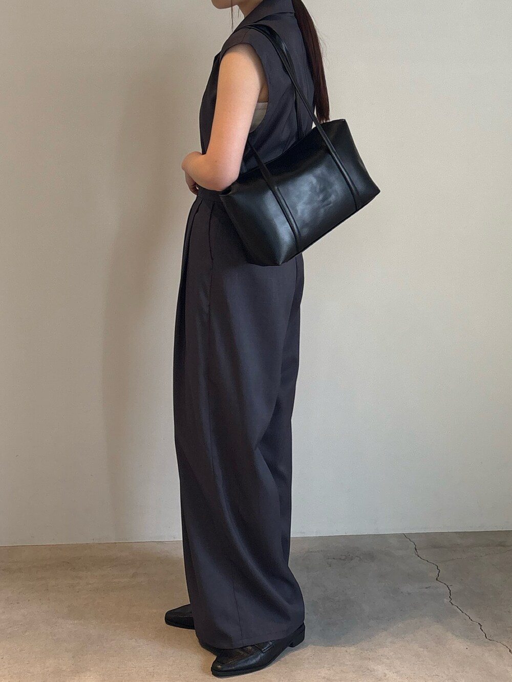 ブラック系のショルダーバッグ、グレー系のパンツドレスを着用したレディースの春コーディネートの3枚目の写真