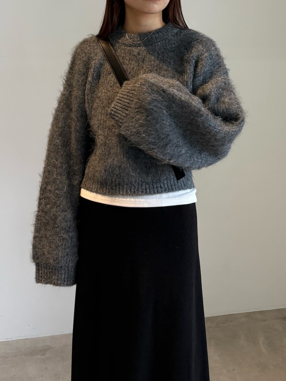 ブラック系のスカート、ブラック系のスリッポン、グレー系のニット/セーターを着用したレディースの秋コーディネートの5枚目の写真