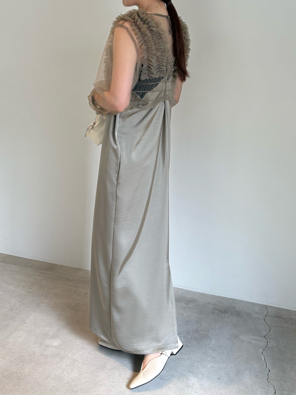 ブラック系のキャミソール、ホワイト系のショルダーバッグ、ベージュ系のドレスを着用したレディースの春コーディネートの4枚目の写真