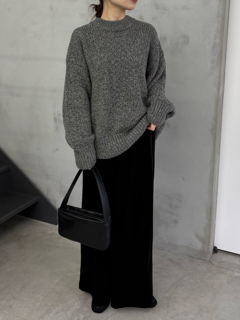 グレー系のニット/セーター、ブラック系のスカート、ブラック系のショルダーバッグを着用したレディースの冬コーディネートの3枚目の写真