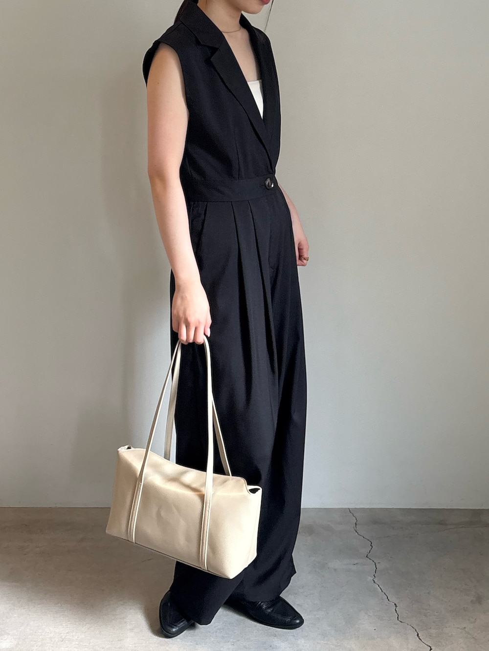 ベージュ系のショルダーバッグ、ホワイト系のキャミソール、ブラック系のパンツドレスを着用したレディースの春コーディネートの2枚目の写真