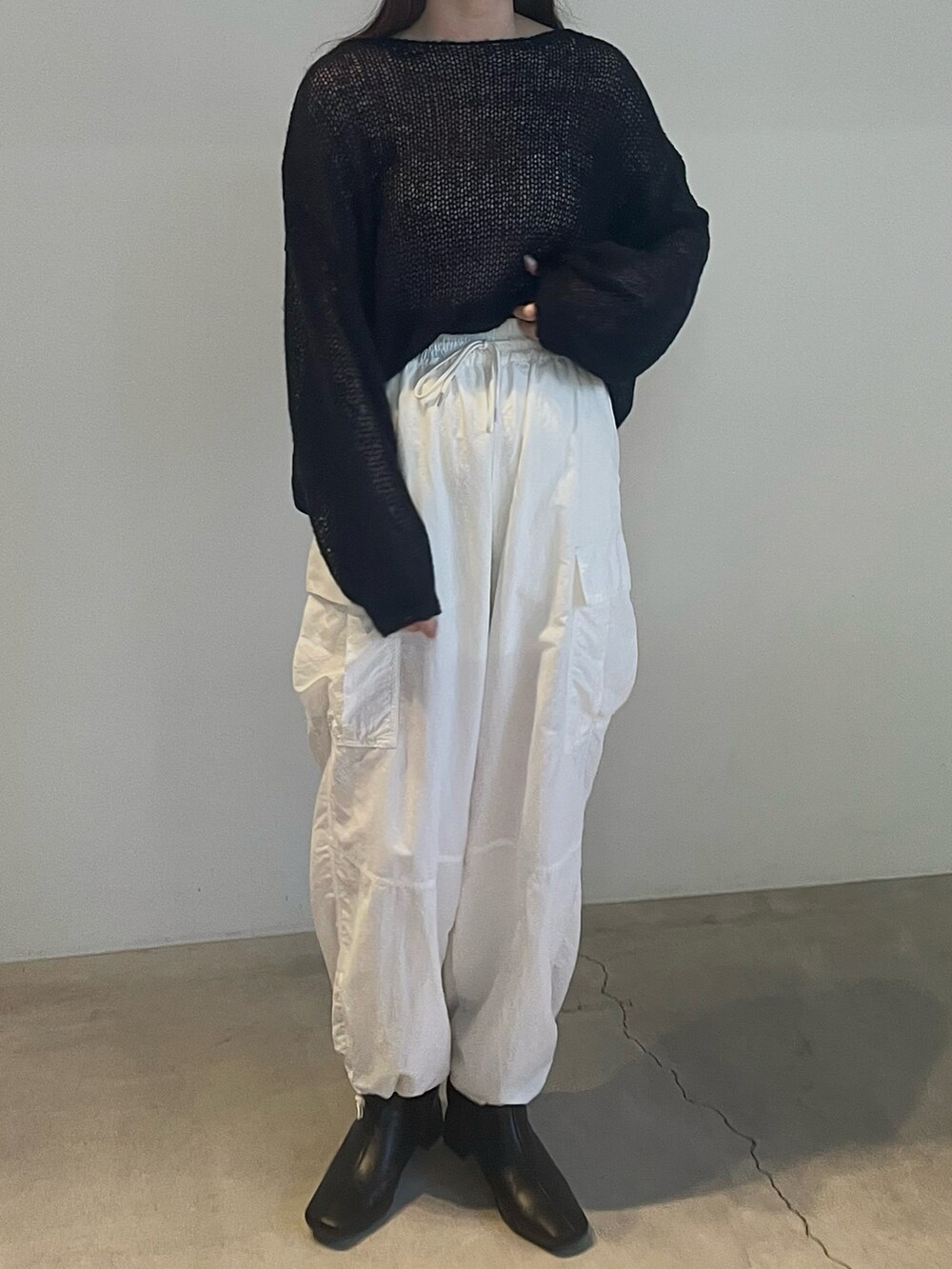 ブラック系のニット/セーター、ホワイト系のカーゴパンツを着用したレディースの夏コーディネートの3枚目の写真