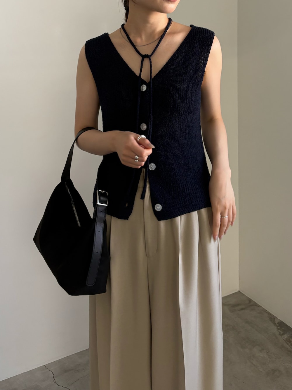 ブルー系のベスト、ベージュ系のスラックス、ブラック系のサンダルを着用したレディースの夏コーディネートの5枚目の写真