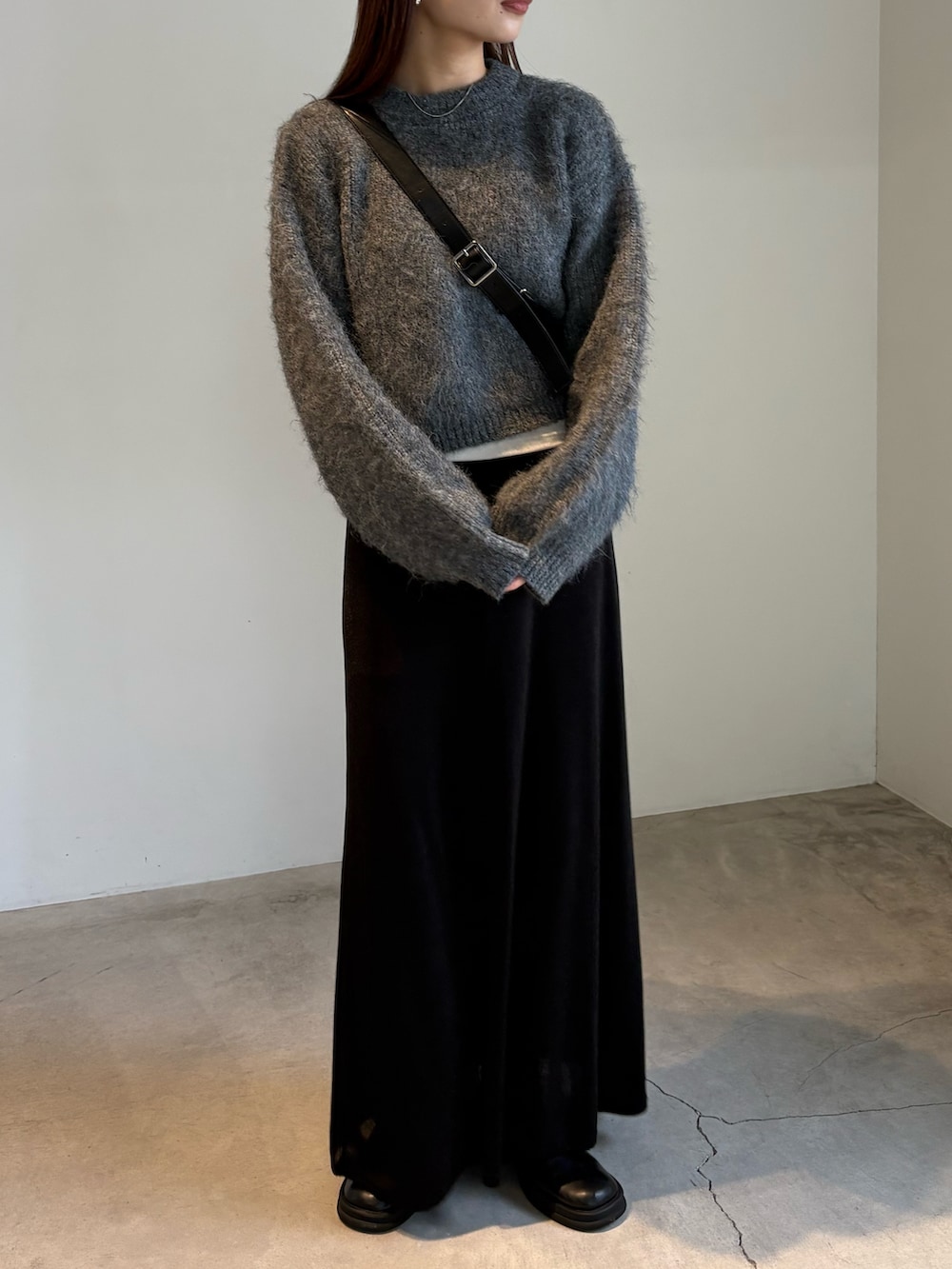 ブラック系のスカート、ブラック系のスリッポン、グレー系のニット/セーターを着用したレディースの秋コーディネートの2枚目の写真