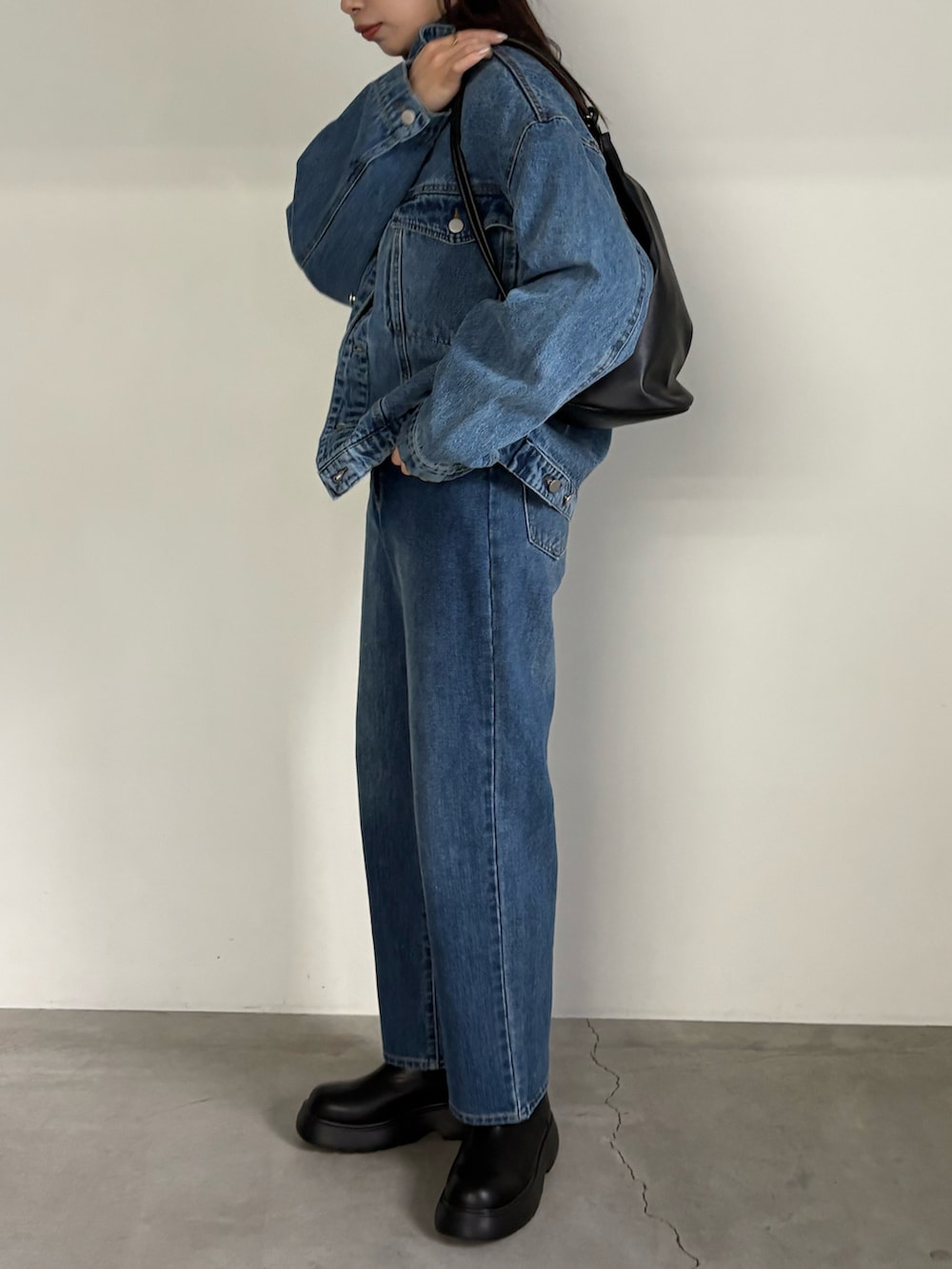 ブルー系のデニムジャケット、ブルー系のデニムパンツ、ブラック系のブーツを着用したレディースの冬コーディネートの2枚目の写真