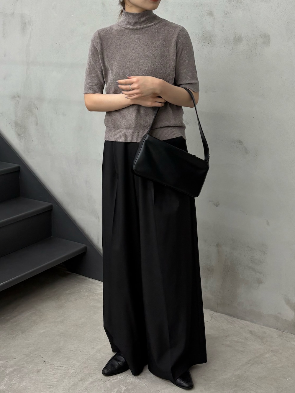 グレー系のニット/セーター、ブラック系のスラックス、ブラック系のショルダーバッグを着用したレディースの秋コーディネートの2枚目の写真