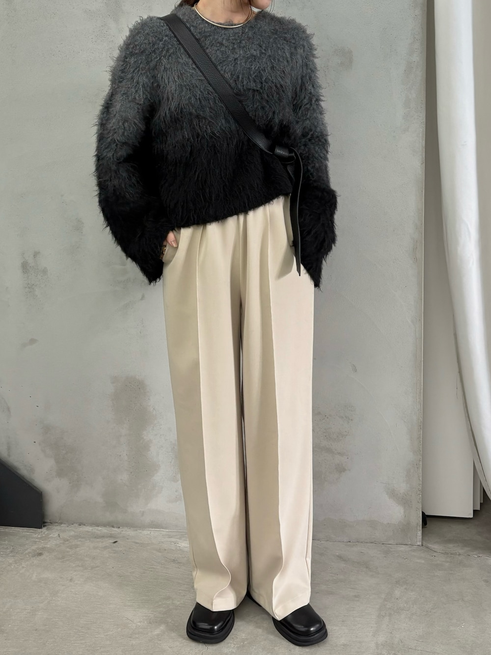 ブラック系のニット/セーター、ブラック系のスリッポン、ブラック系のショルダーバッグを着用したレディースの秋コーディネートの2枚目の写真