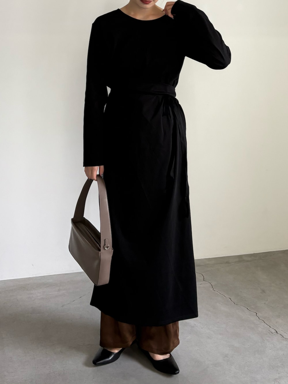 ブラウン系のスラックス、ブラウン系のショルダーバッグ、ブラック系のサンダルを着用したレディースの夏コーディネートの2枚目の写真