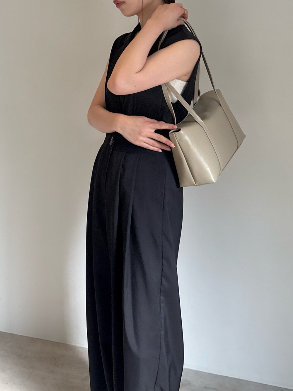 ベージュ系のショルダーバッグ、ホワイト系のキャミソール、ブラック系のパンツドレスを着用したレディースの春コーディネートの4枚目の写真