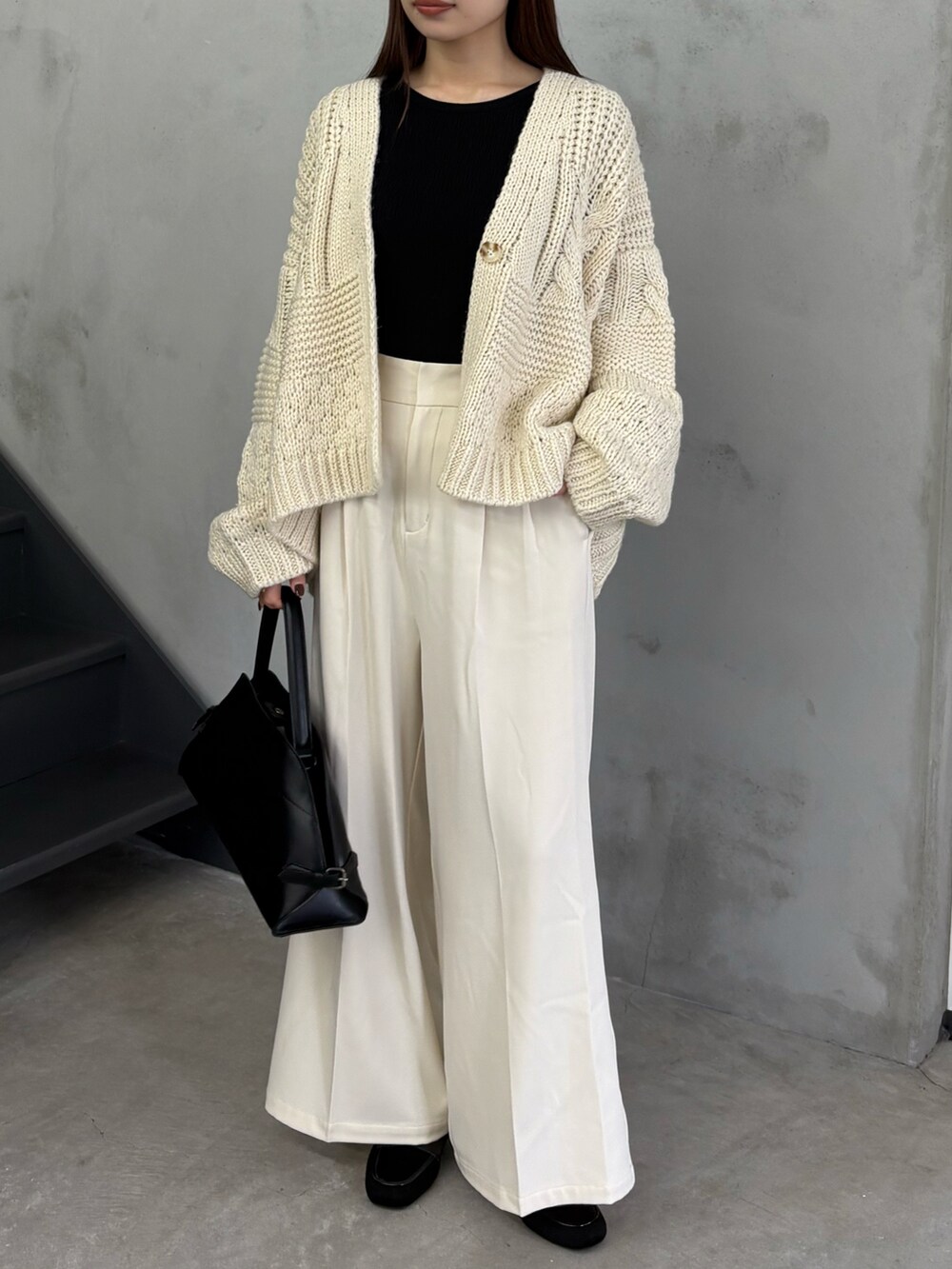 ホワイト系のカーディガン/ボレロ、ホワイト系のスラックス、ブラック系のハンドバッグを着用したレディースの秋コーディネートの2枚目の写真