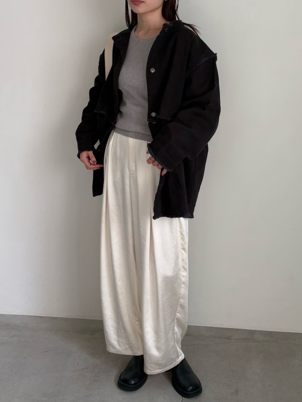 ブラック系のデニムジャケット、グレー系のTシャツ/カットソー、ホワイト系のスラックスを着用したレディースの冬コーディネートの2枚目の写真