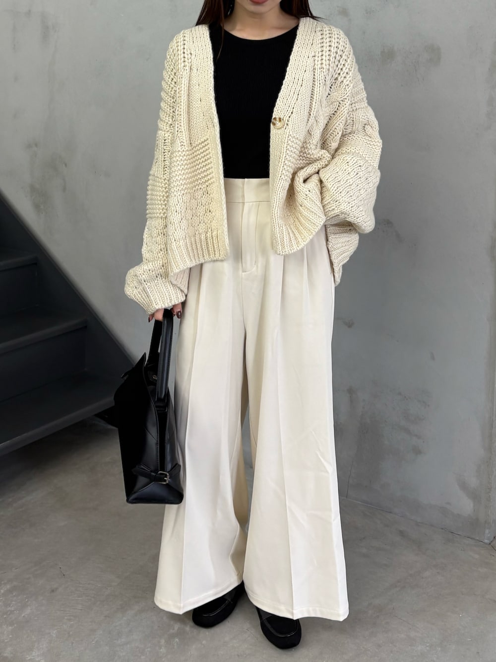 ホワイト系のカーディガン/ボレロ、ホワイト系のスラックス、ブラック系のハンドバッグを着用したレディースの秋コーディネートの3枚目の写真