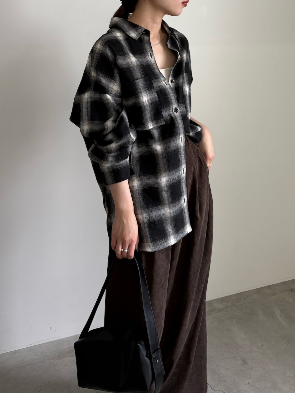 ブラック系のシャツ/ブラウス、ブラウン系のスラックス、ホワイト系のキャミソールを着用したレディースの夏コーディネートの3枚目の写真