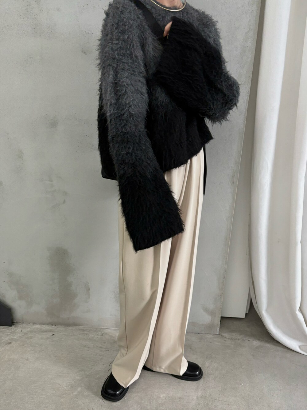 ブラック系のニット/セーター、ブラック系のスリッポン、ブラック系のショルダーバッグを着用したレディースの秋コーディネートの3枚目の写真