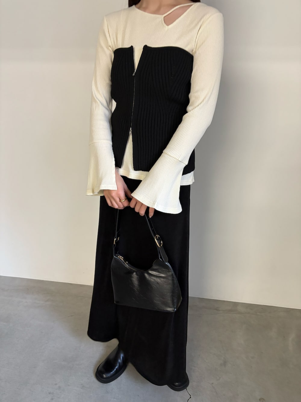 ブラック系のベスト、ブラック系のスカート、ブラック系のハンドバッグを着用したレディースの冬コーディネートの5枚目の写真