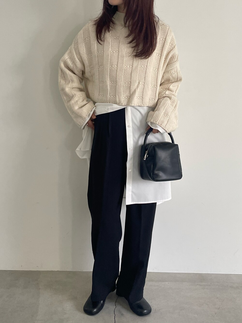 ホワイト系のニット/セーター、ホワイト系のシャツ/ブラウス、ブラック系のスラックスを着用したレディースの冬コーディネートの2枚目の写真