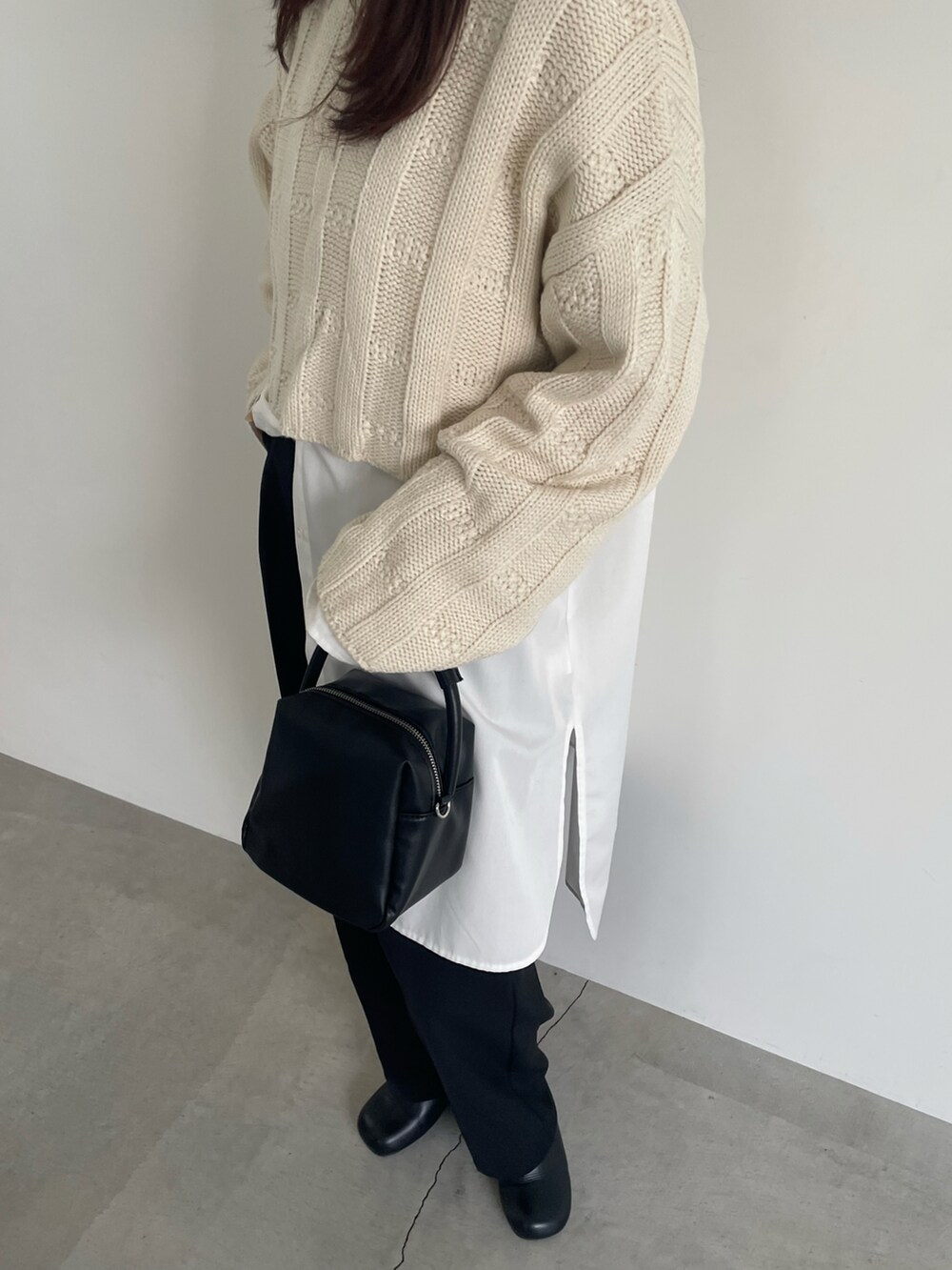 ホワイト系のニット/セーター、ホワイト系のシャツ/ブラウス、ブラック系のスラックスを着用したレディースの冬コーディネートの3枚目の写真