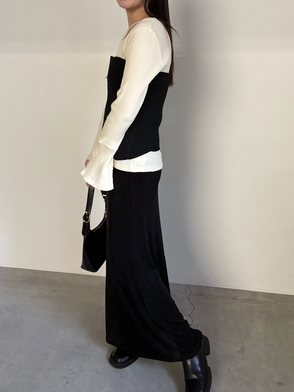 ブラック系のベスト、ブラック系のスカート、ブラック系のハンドバッグを着用したレディースの冬コーディネートの3枚目の写真